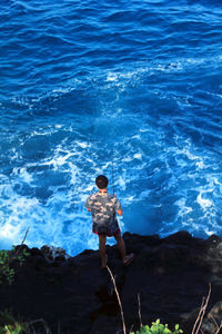 Man standing on rock in sea