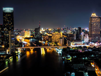 Illuminated buildings in city against sky at night