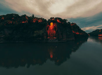 Reflection of rocks in lake against sky during sunset