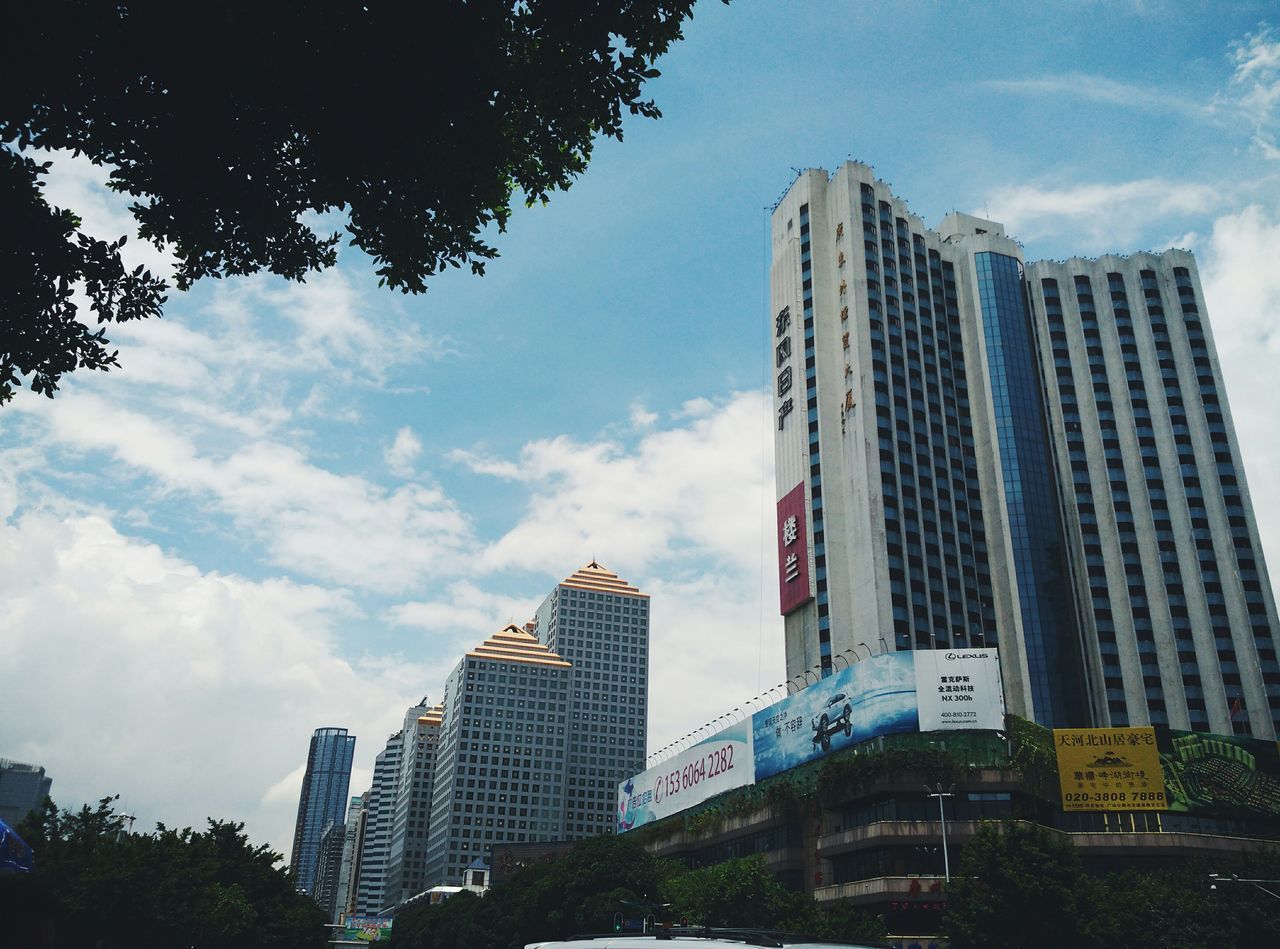 building exterior, architecture, built structure, city, skyscraper, low angle view, tall - high, modern, tower, office building, sky, tree, building, cloud - sky, city life, tall, urban skyline, cloud, day, financial district