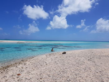 Man swimming in sea against cloudy sky