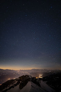 Scenic view of snowcapped mountains against sky at night