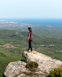 Woman standing on rock against sky