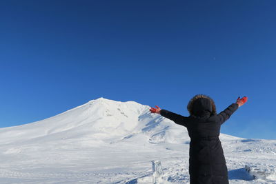 Man standing on snow covered mountain against blue sky