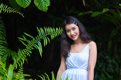 Portrait of young woman standing by plants