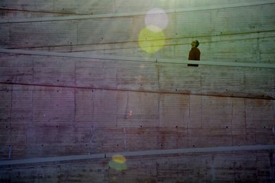 Low angle view of man looking up while standing on staircase during sunny day