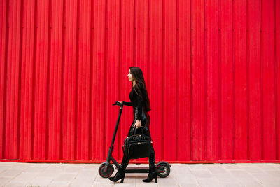 Full length side view of a man walking against red wall