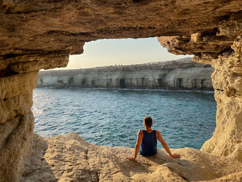 Rear view of young man staring at the sea in cape greco, cyprus
