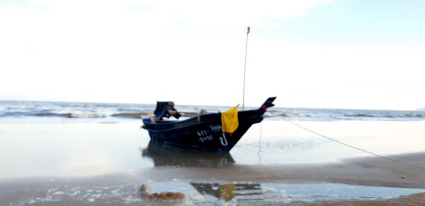 Man on boat at beach against sky