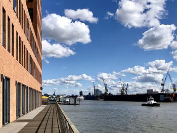 Boats moored at harbor by buildings against sky