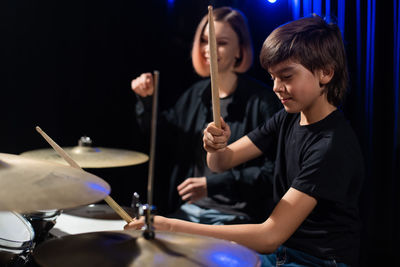 Boy playing drum sitting by teacher