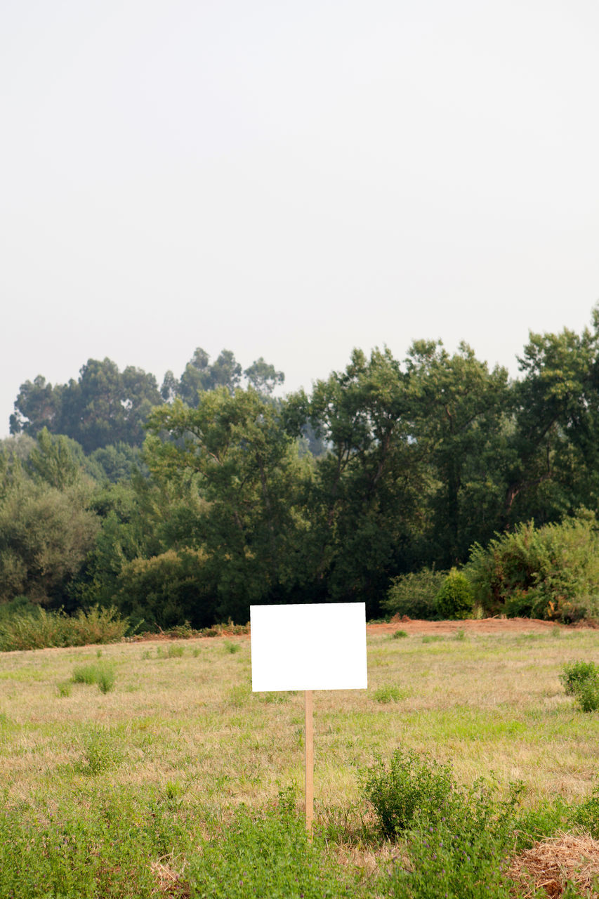 SIGN BOARD ON FIELD AGAINST SKY