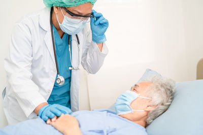 Doctor examining patient lying on bed