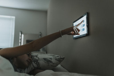 Girl controlling temperature of bedroom through digital tablet at smart home