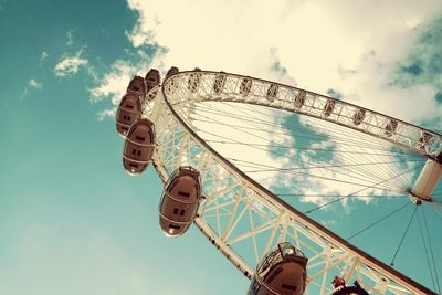 Low angle view of ferris wheel against cloudy sky