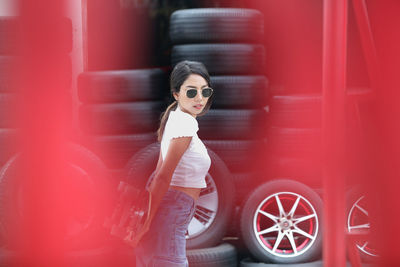 Portrait of woman standing by red car