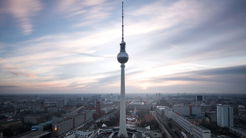 Fernsehturm in city against sky during sunset