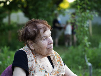 Thoughtful senior woman looking away while sitting in back yard