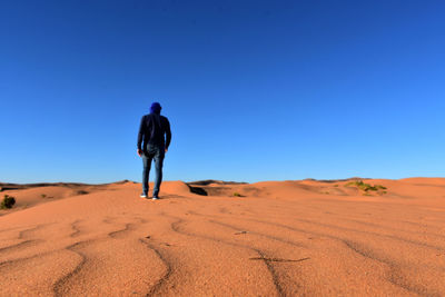 Rear view of man on desert against clear sky