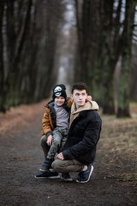 Full length of young man with boy in forest