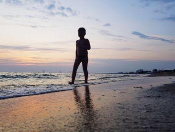 Full length of man standing on beach during sunset