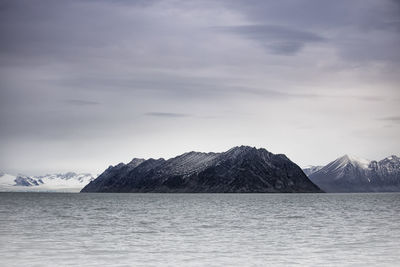 Scenic view of sea and snowcapped mountains against sky