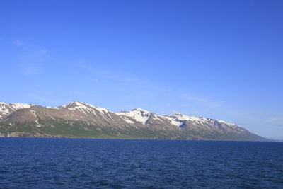 Scenic view of snowcapped mountains against blue sky