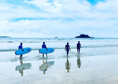 People walking on beach against sky