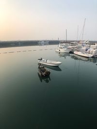 Sailboats moored on harbor against clear sky