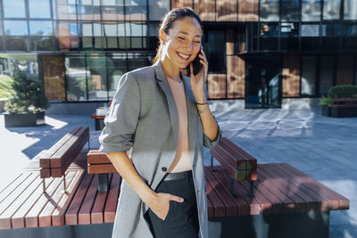 Happy businesswoman with hand in pocket talking on mobile phone