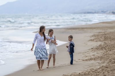 Smiling mother and kids walking at beach