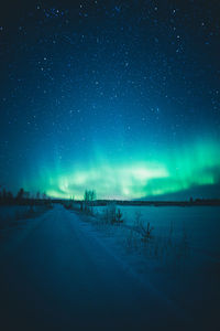 Scenic view of snow covered land against sky during aurora borealis