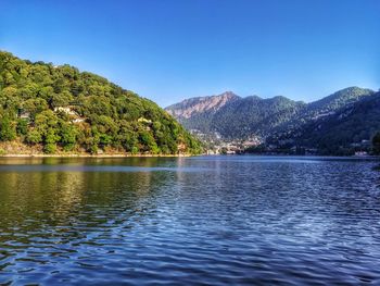 Scenic view of lake and mountains against clear blue sky