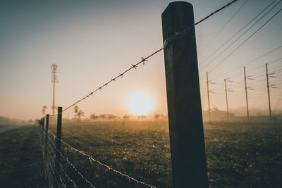 Electricity pylon on field against sky during sunset