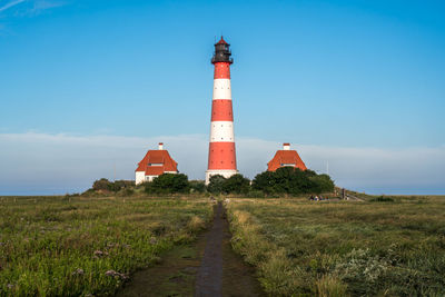 Lighthouse by sea against sky