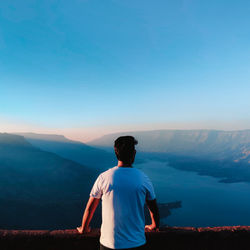 Rear view of man looking at mountains against sky