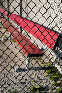 Close-up of empty red bench against brick wall