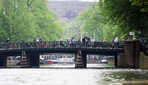 People on bridge over river during rainy season