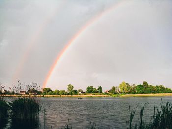 Scenic view of rainbow over lake against sky
