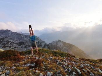 Rear view of man standing on mountain against sky