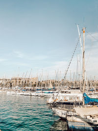 Sailboats moored in sea against sky