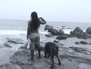 Rear view of woman with dog standing on beach