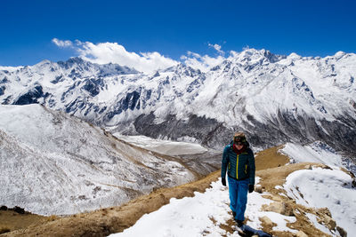 Man standing on snowcapped mountain against sky