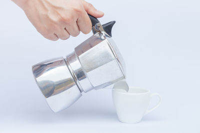 Close-up of hand holding drink against white background