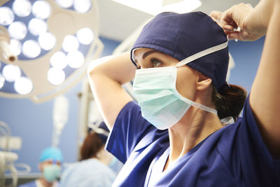 Low angle view of doctor tying surgical mask in hospital