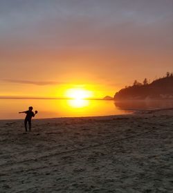 Silhouette man on beach against sky during sunset