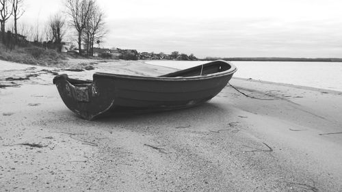 Boat moored on beach against sky