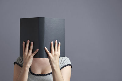 Low section of person on book against gray background