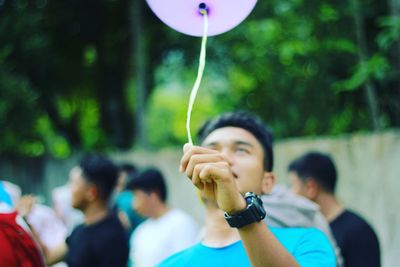 Young man holding balloon at park