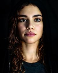 Close-up portrait of young woman against black background